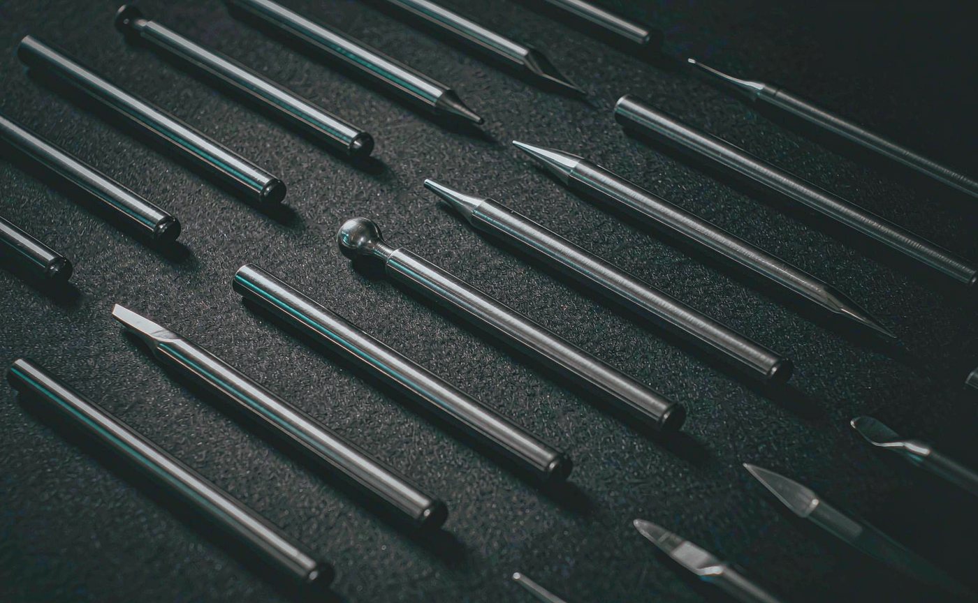 Polished stainless steel precision instruments arranged in rows on a dark surface